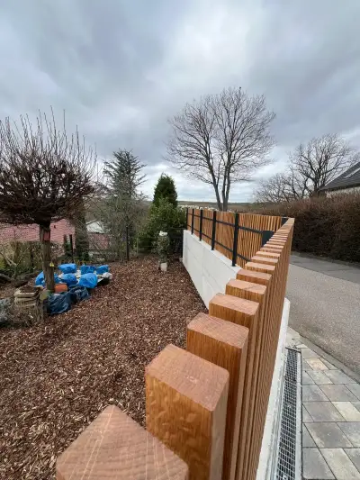 Stahlzaun mit Holzfüllung entlang eines Gartens