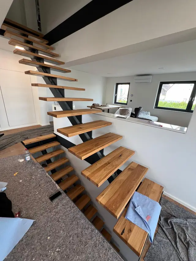 Freitragende Stahltreppe mit Holzstufen im Rohbau